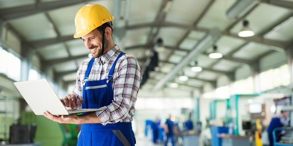 men working on laptop in manufacturing plant