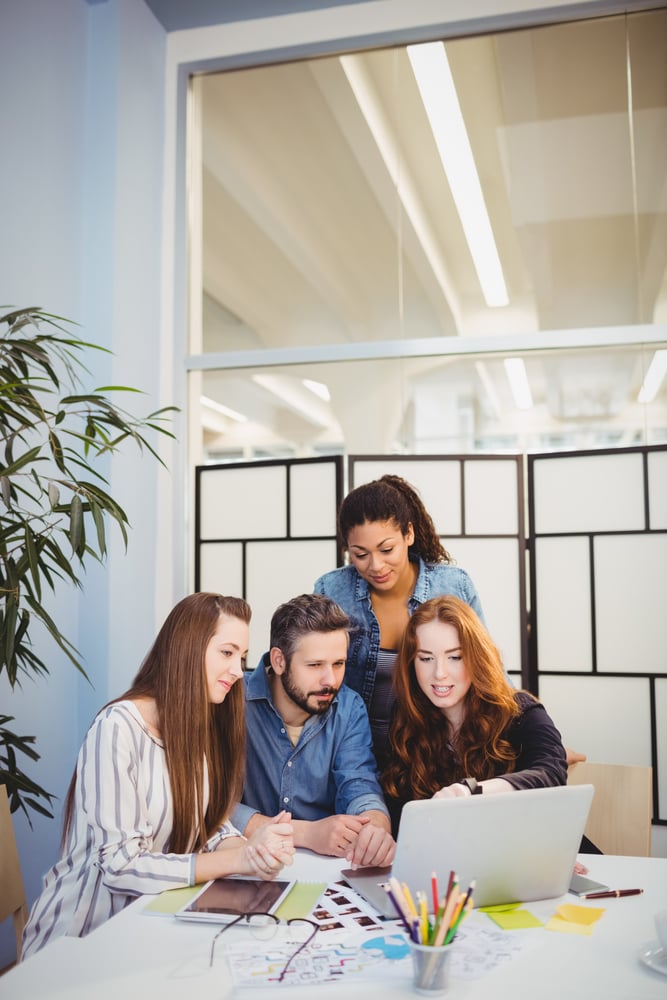 Stylish business people using laptop in meeting room at creative office