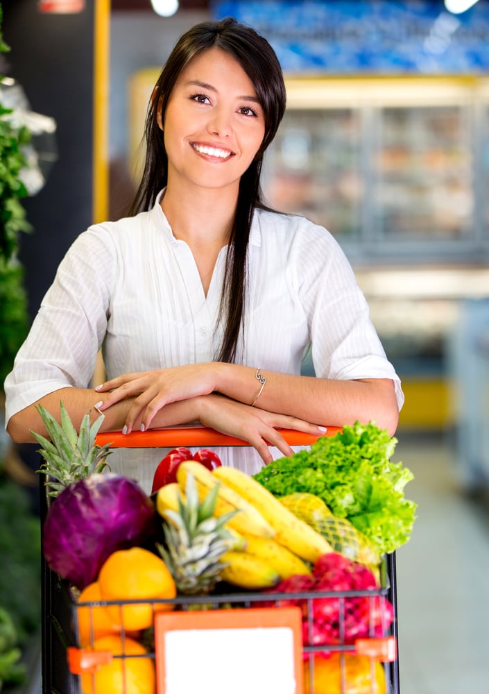 Woman at the supermarket with a shopping cart full of groceries